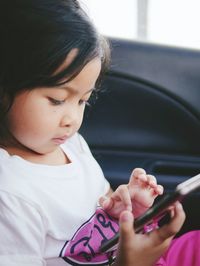 Close-up of girl using phone while sitting in car