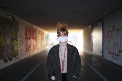 Portrait of woman standing against graffiti wall