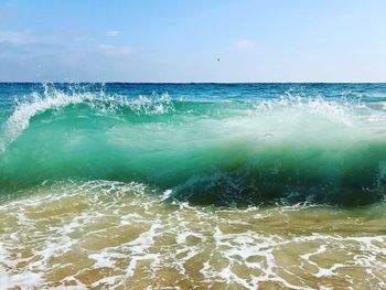 Scenic view of sea waves splashing against sky