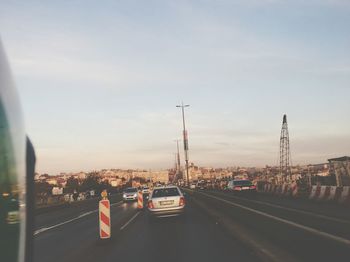 Cars on street in city against sky