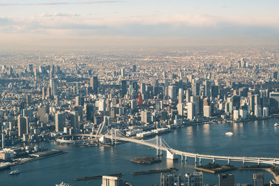 Aerial view of tokyo tower surrounded by water and buildings against sky