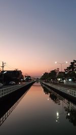 Illuminated bridge over river against sky during sunset