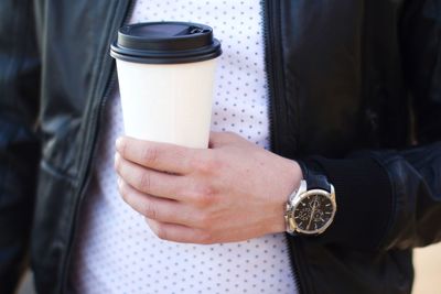 Midsection of man wearing jacket while holding disposable cup