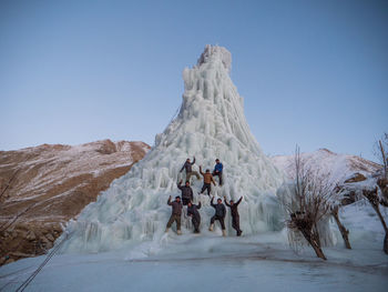 People on snowcapped mountain against clear sky