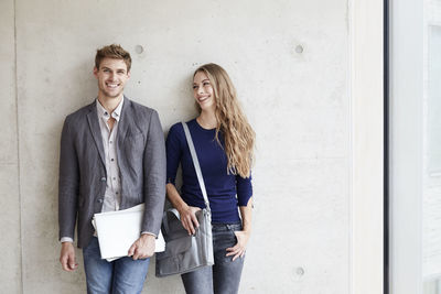 Smiling young couple at concrete wall