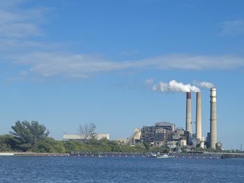 Smoke emitting from factory against sky