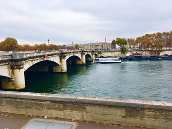 Arch bridge over river against sky in city