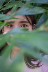 Close-up portrait of woman with brown eyes seen through leaves