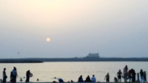 Silhouette people by sea against clear sky