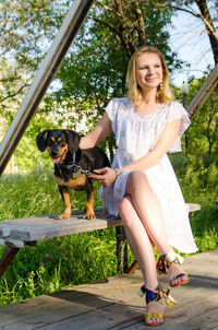 Young woman with dog sitting on swing outdoors