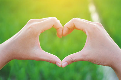 Cropped hands of woman making heart shape