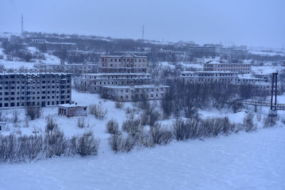 Snow covered trees and buildings against sky