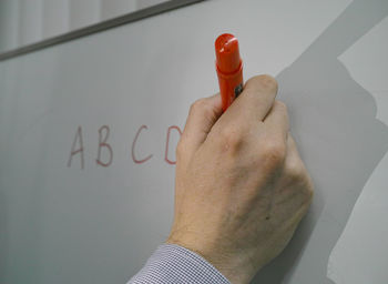 Close-up of hand writing on whiteboard