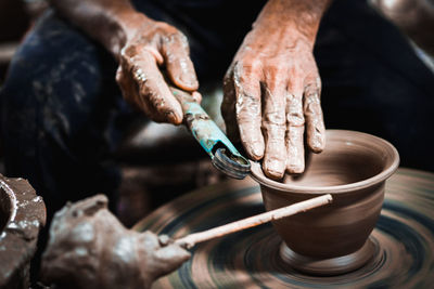 Midsection of man working on pottery wheel