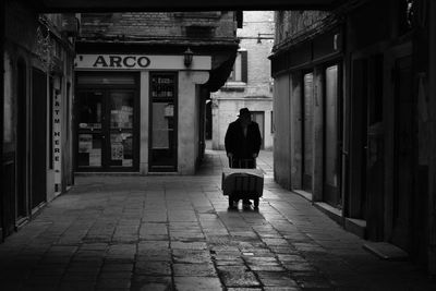 Rear view of man walking on street amidst buildings