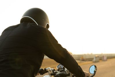 Rear view of man skateboarding against sky