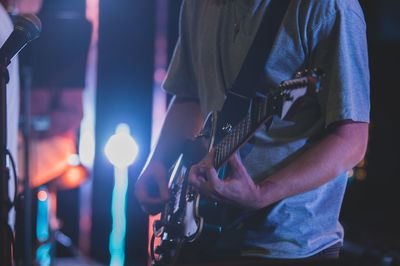 Midsection of man playing guitar on stage