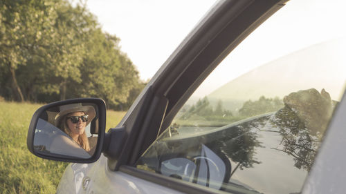 Reflection of woman on side-view mirror of car