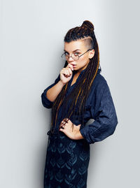 Portrait of young woman standing against white background