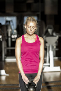 Young woman exercising with kettlebell in health club
