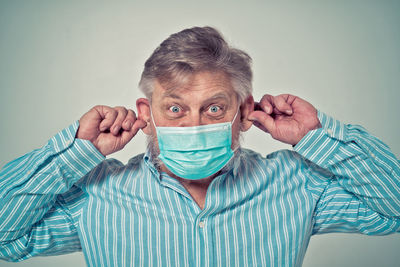 Portrait of man covering face against blue background