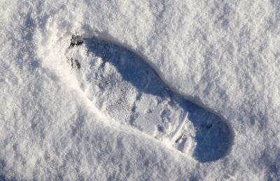 Footsteps of male shoes in fresh white snow in winter.