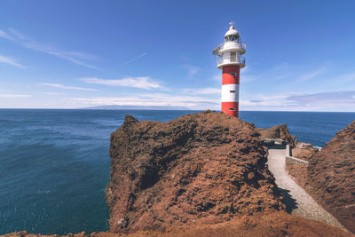 Lighthouse by sea against sky