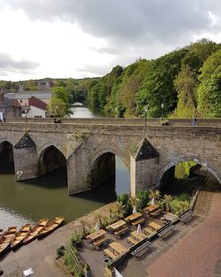 Arch bridge over river against cloudy sky