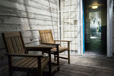 Empty chairs and table against wall with shadows at outdoor cafe 