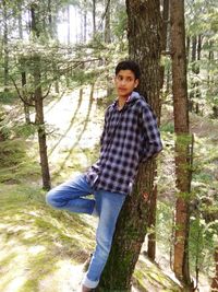 Portrait of young man on tree trunk in forest