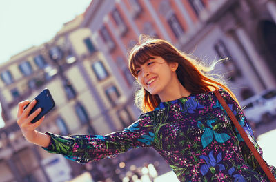 Portrait of smiling young woman using smart phone outdoors