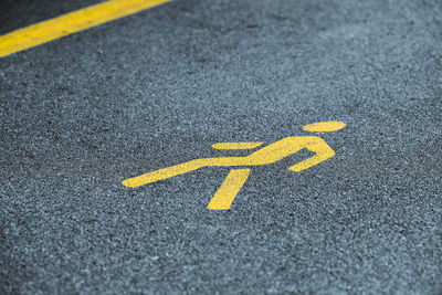 Yellow pedestrian sign on sidewalk, safe road traffic near highway. pedestrian road sign on asphalt