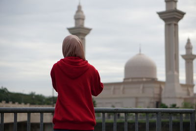 Rear view of woman standing against mosque