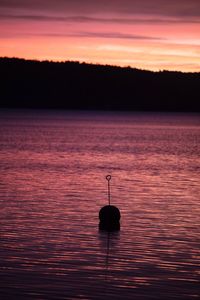 Silhouette boat in water against sky during sunset