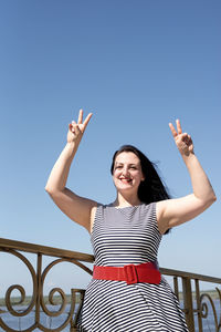 Happiness concept. beautiful young woman opened her hands at the blue sky showing peace gesture