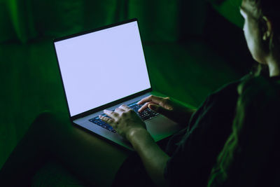 Midsection of woman using laptop in darkroom