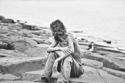 Woman sitting on rock at beach
