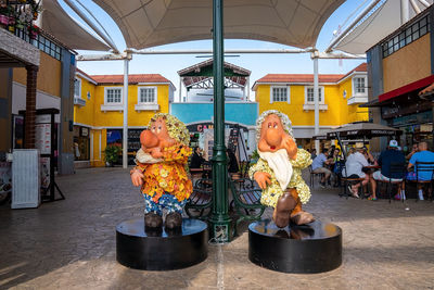 Men sitting at market stall against buildings