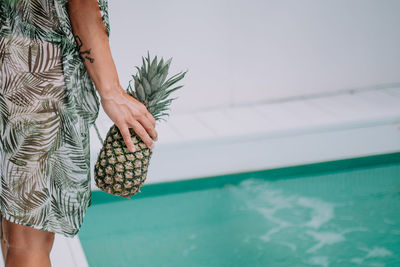 Midsection of woman holding umbrella by swimming pool