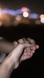 Close-up of holding hands at night