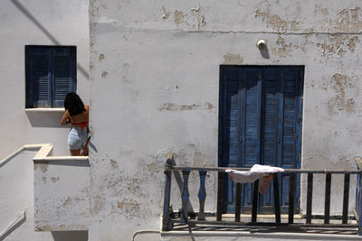 Woman standing by window of building