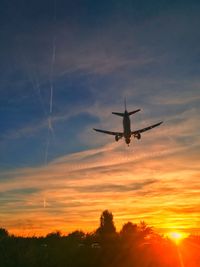 Low angle view of silhouette airplane against sky during sunset
