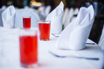 Red drink in glasses by napkins arranged in table at restaurant