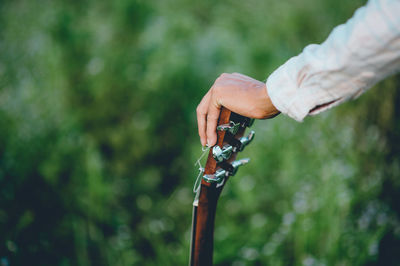 Cropped hand of man holding guitar in park