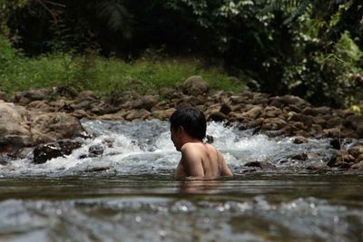 Shirtless man swimming in water