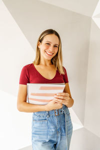 Portrait of young woman standing against wall