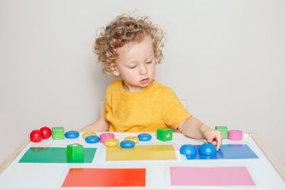 Baby toddler playing sorting organising objects blocks with specific colors. early age education. 
