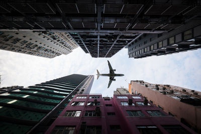 Airplane flying over buildings against sky