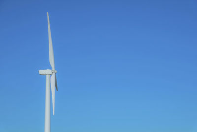 Low angle view of windmill against clear blue sky
