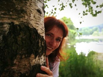 Portrait of young woman against tree trunk